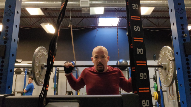 Robbie Ferguson doing barbell squats at the gym, with 75 lbs total weight.